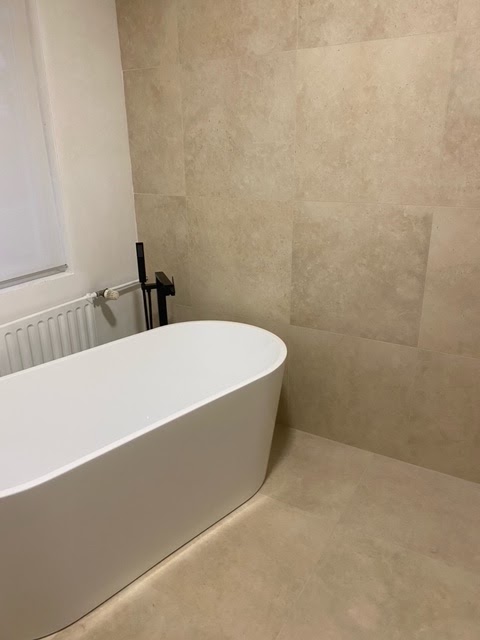 Badkamer met vrijstaand bad en beige wandtegels in natuursteenlook
