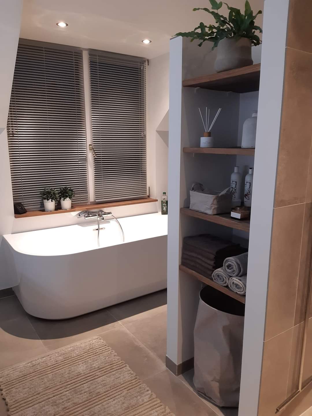 Badkamer met vrijstaand bad, open kast en betonlook tegels