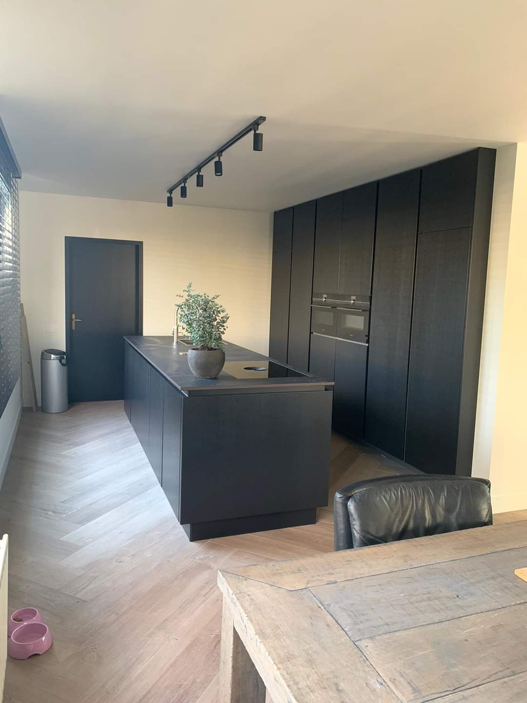 Keuken met zwart kookeiland op een visgraat tegelvloer in houtlook